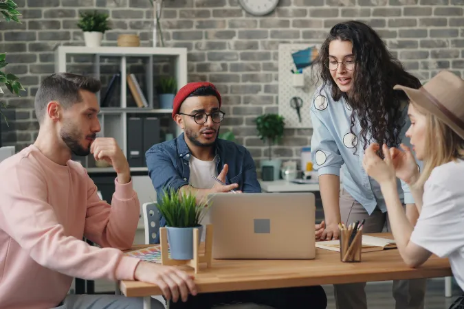 Equipe reunida em uma mesa, analisando o planejamento do projeto em um notebook