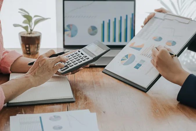 Duas pessoas analisando gráficos de desempenho em planilhas e telas com indicadores visuais