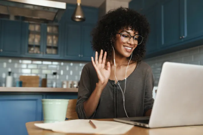 Mulher sorrindo em videoconferência com laptop e fone de ouvido
