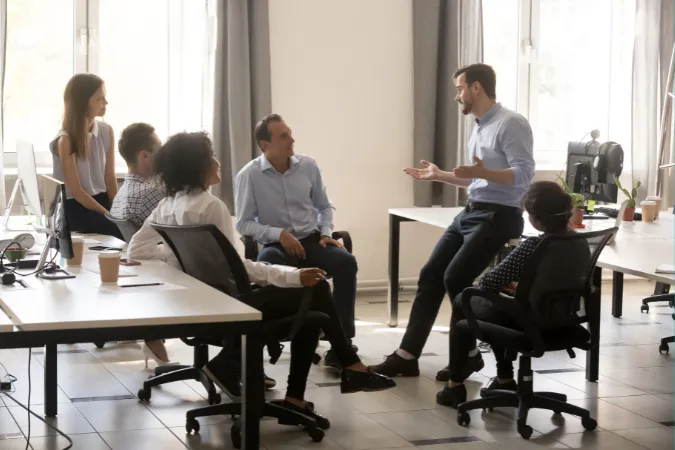 Líder conversando com equipe em ambiente de escritório, orientando sobre priorização de tarefas com base na matriz de Eisenhower.