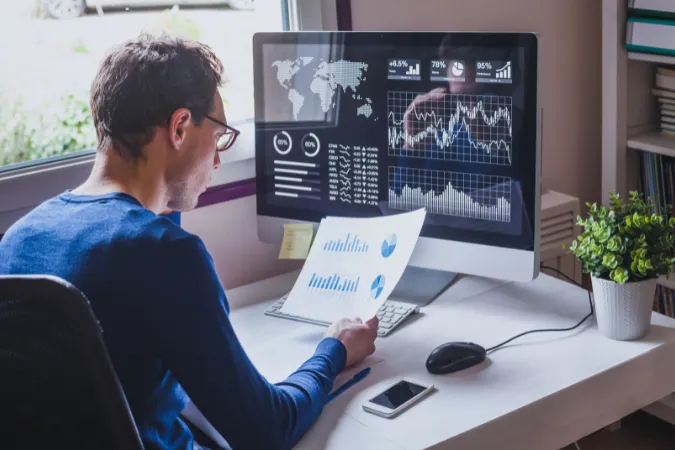 Profissional analisando gráficos de desempenho em tela de computador.