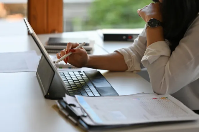 Profissional usando notebook para gerenciar planilhas e informações de projetos.
