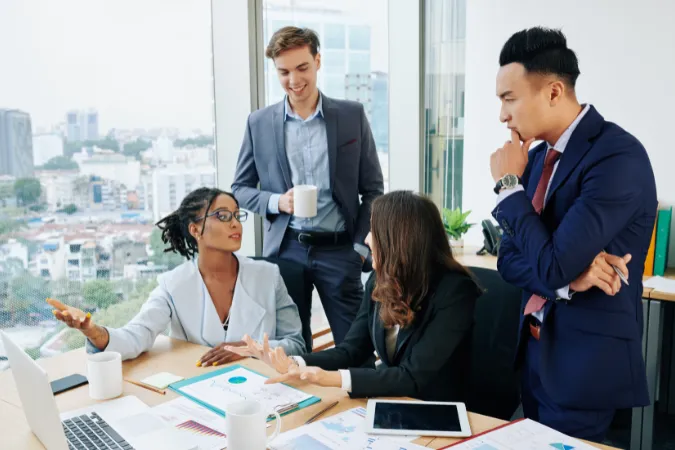 Equipe de consultoria reunida em escritório moderno discutindo planilhas de custos e indicadores.
