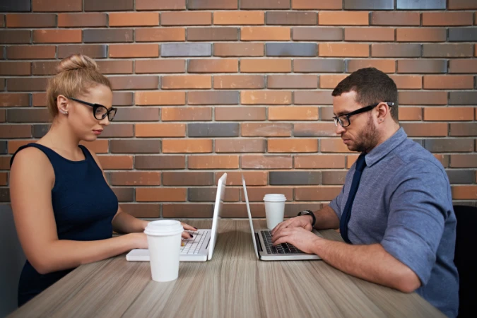Dois profissionais trabalhando lado a lado em notebooks, representando sessões coletivas de deep work.