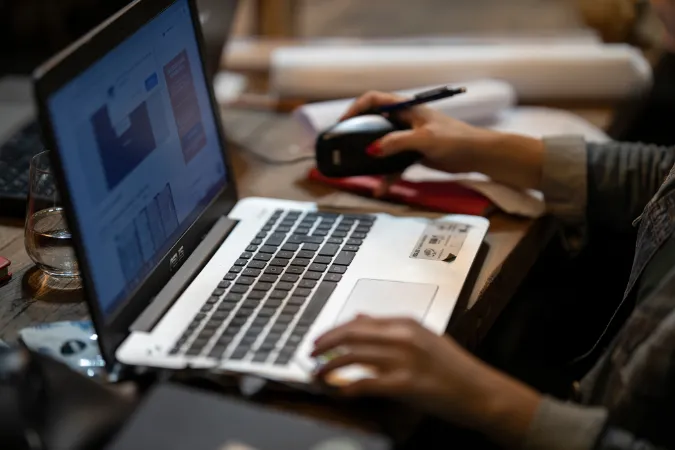Pessoa utilizando notebook em ambiente de trabalho para organizar informações de desk research em projetos.