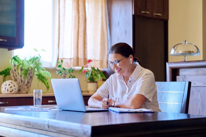 Colaboradora remota trabalha com notebook em home office, representando o uso de software de gestão para organizar times híbridos.