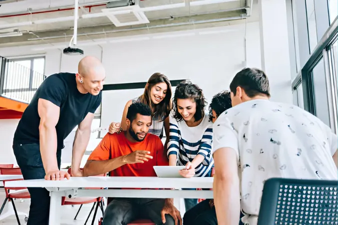 Equipe reunida em volta de uma mesa analisando entregas de um projeto em tablet.