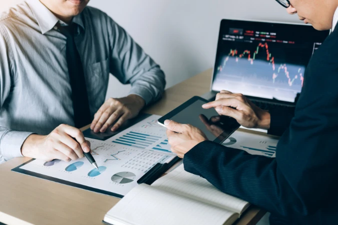 Duas pessoas analisando gráficos e relatórios corporativos em um software de gestão de projetos.