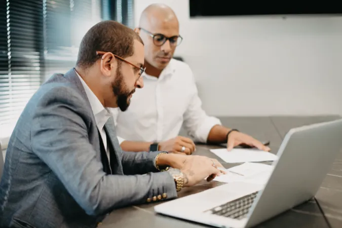 Consultores analisando documentos e dados em notebook durante diagnóstico de projeto, estruturando entregáveis essenciais de consultoria para orientar decisões estratégicas.