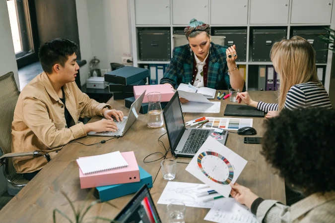 Equipe não técnica reunida em mesa de trabalho com laptops, documentos e planejamento visual