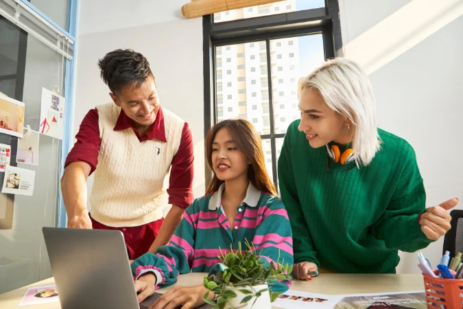 Equipe diversa analisando tarefas em laptop em um ambiente de trabalho colaborativo