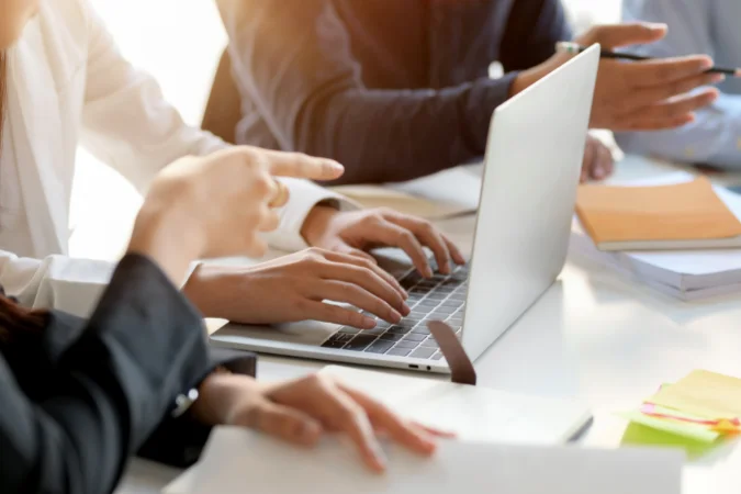 Equipe utilizando software de gestão de projetos no computador para priorizar tarefas