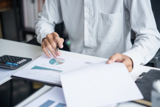 Profissional analisando relatórios financeiros e indicadores para acompanhar a rentabilidade de projetos de serviços.