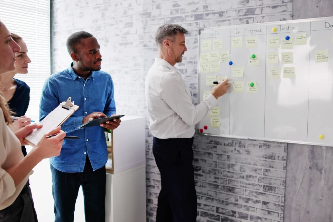 Equipe analisando quadro Kanban com tarefas organizadas por etapas, aplicando metodologias ágeis no dia a dia
