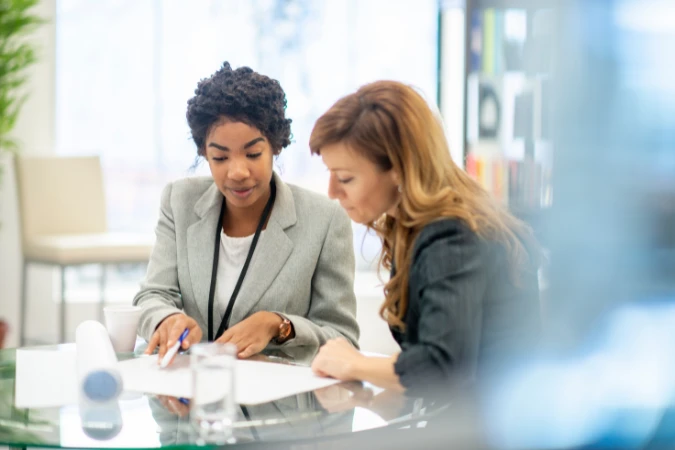 Duas profissionais revisando documentos e indicadores financeiros em reunião de planejamento