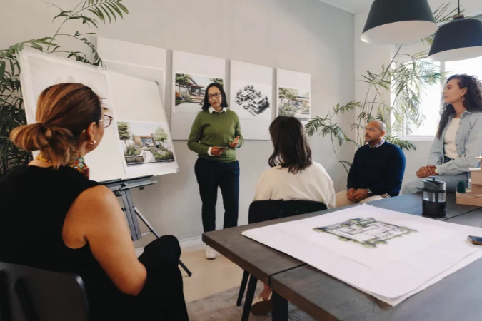 Equipe analisando plantas e discutindo escopo técnico em sala de reunião