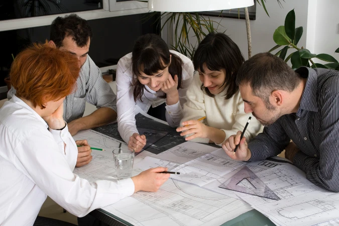 Equipe de arquitetura reunida analisando plantas e discutindo soluções técnicas