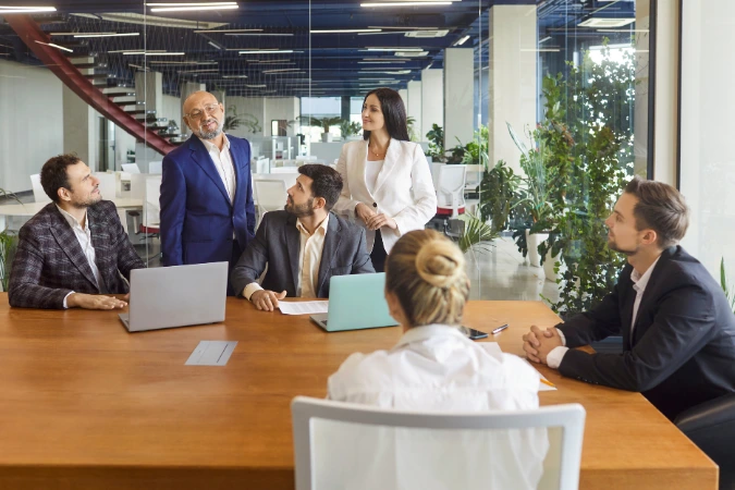 Equipe reunida em reunião estratégica discutindo decisões de projeto para distribuir responsabilidades entre profissionais