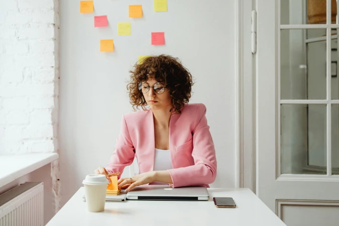 Profissional organizando tarefas com post-its em um ambiente de trabalho, representando planejamento e gestão de tempo.