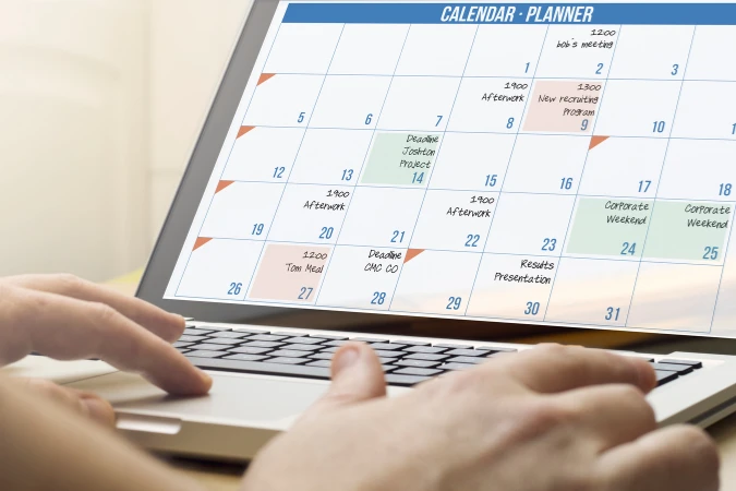Calendário digital aberto em um laptop mostrando tarefas organizadas ao longo do mês.