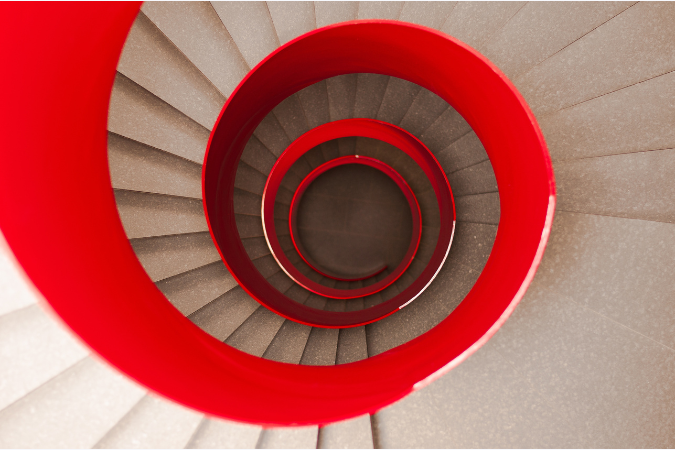 "Escada em espiral com guarda-corpo vermelho vibrante, demonstrando o uso expressivo da cor vermelha em elementos arquitetônicos estruturais."