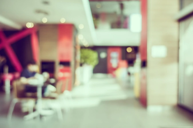 Interior de cafeteria com ambiente desfocado e elementos em vermelho nas paredes, sugerindo uma atmosfera energética e moderna voltada para o consumo rápido.