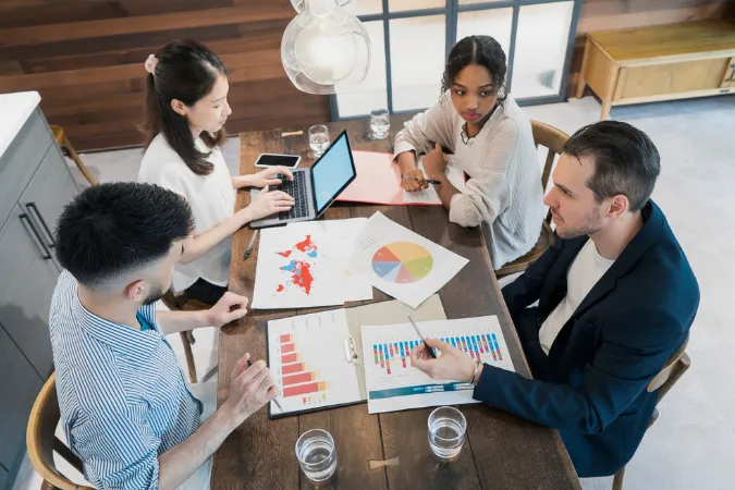 Equipe de projeto analisando gráficos coloridos, mapas e métricas de desempenho em uma reunião de gestão
