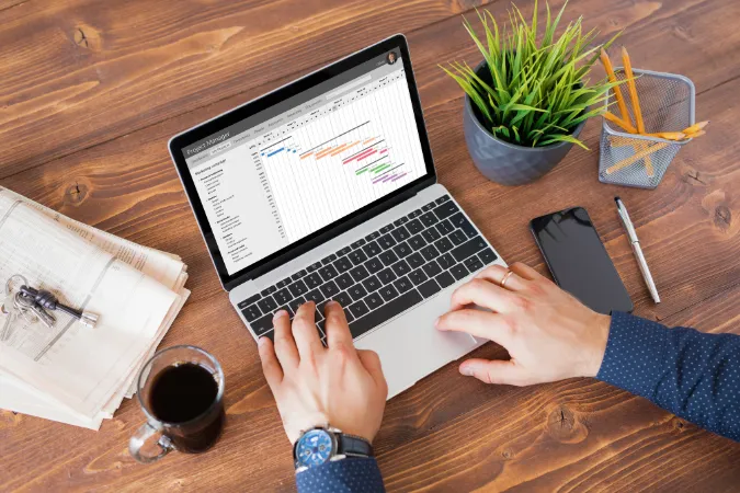 Pessoa visualizando o cronograma de um projeto em um gráfico de Gantt na tela do notebook