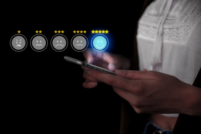 Pessoa segurando smartphone avaliando com cinco estrelas em uma interface digital de feedback