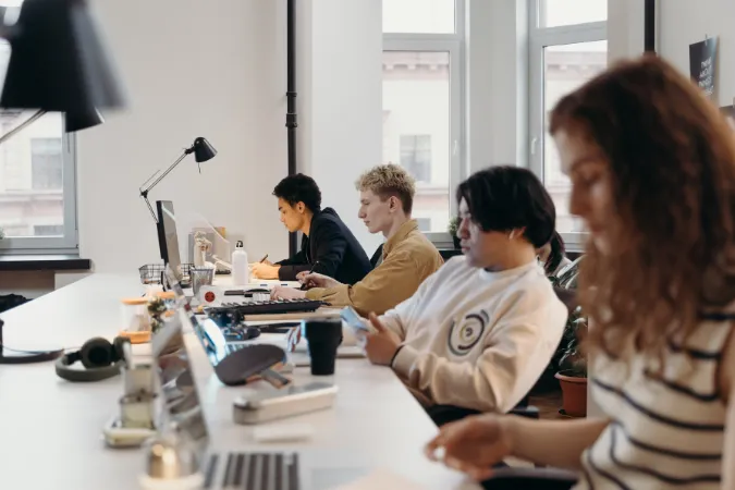 Pessoas de diferentes perfis trabalhando em um escritório moderno com notebooks e foco nas tarefas