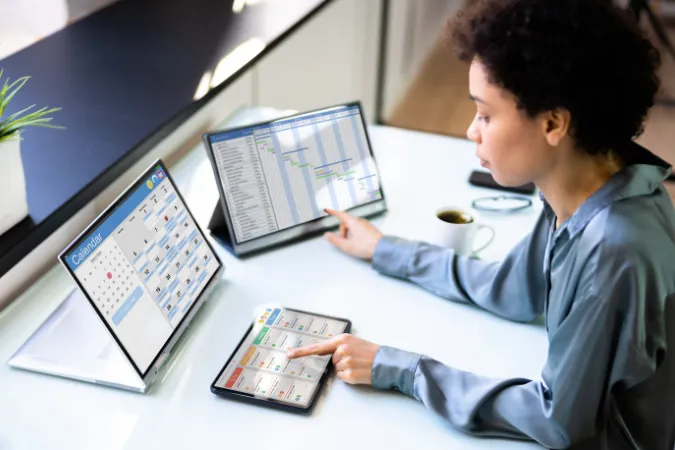 Profissional de tecnologia usando sistemas integrados com Kanban, calendário e cronograma Gantt.