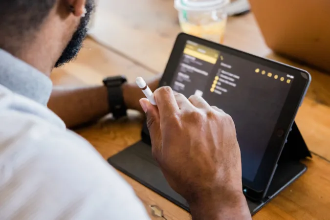 Profissional utilizando tablet com caneta digital para organizar tarefas em aplicativo de notas