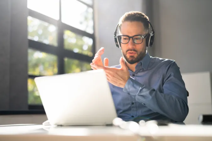 Vendedor explicando proposta com confiança em videoconferência, usando fones de ouvido e computador portátil