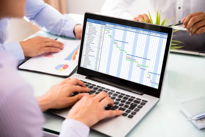 Profissional analisando cronograma com gráfico de Gantt em software de gestão de projetos